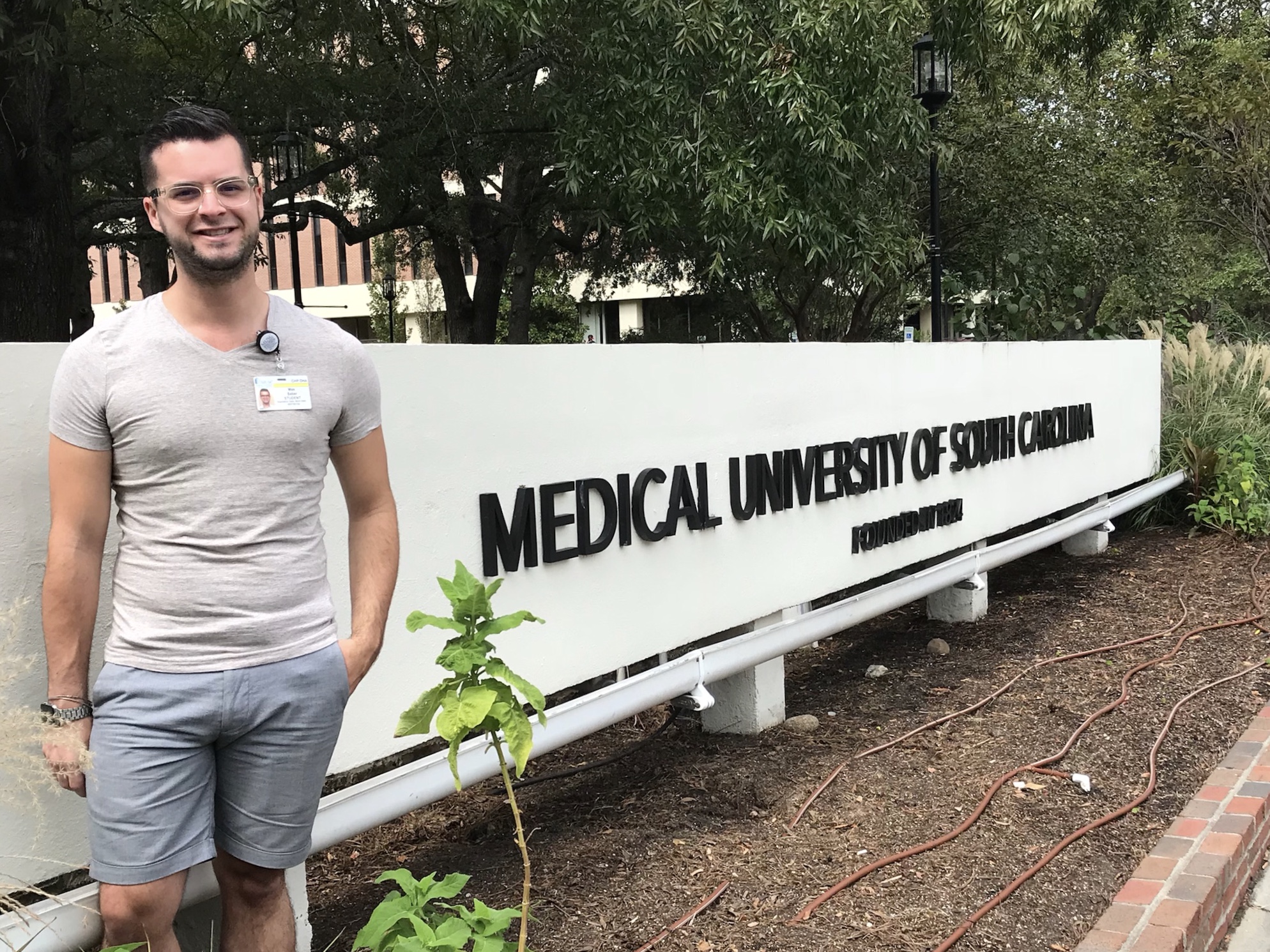 Max Saber standing in front of a stone sign reading Medical University of South Carolina